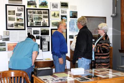 People milling around a table and a wall filled with pictures and items